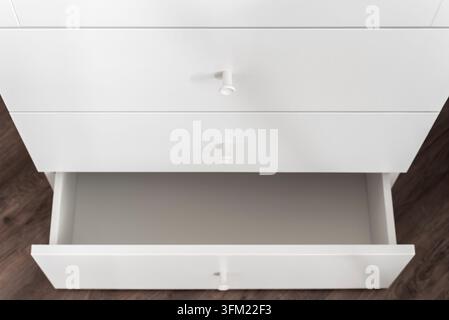 Minimaler weißer Schrank mit einer einzigen offenen Schublade und leerem Innenraum. Sauberes modernes Detail und Speicherkonzept Stockfoto