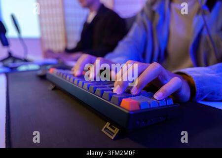 Eine Nahaufnahme fängt Hände ein, die aktiv auf einer mechanischen Tastatur tippen, und betont die Präzision beim Spielen oder bei der Arbeit Stockfoto