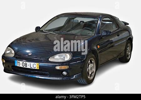 Dunkelblaues Mazda MX-3 Sportwagen-Coupé auf einem sauberen weißen Hintergrund geparkt Stockfoto