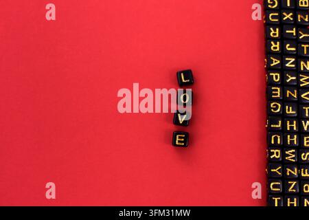 Das Wort Liebe in Holzbuchstaben geschrieben. Alphabetbuchstaben auf einem Würfel. Auf rotem Hintergrund. Kopierraum Stockfoto