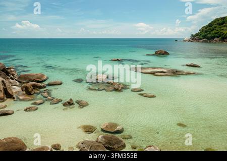 Meerwasser mit Felsbrocken an einem tropischen Strand Stockfoto