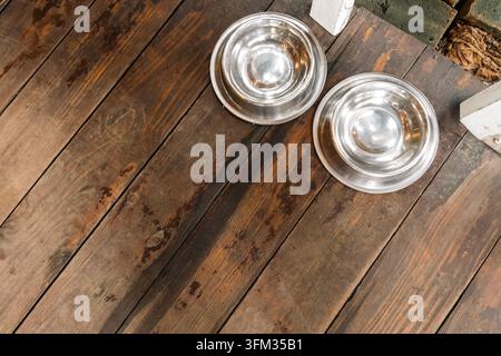 Zwei leere Edelstahl-Haustiernäpfe auf Holzboden mit Platz für Text Stockfoto