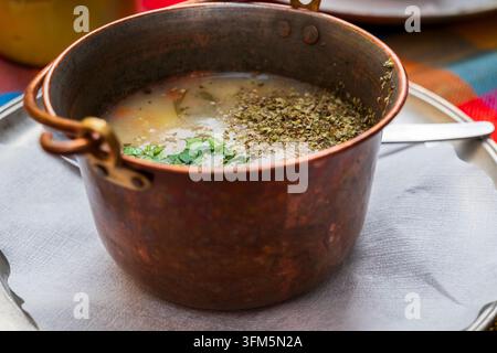 Kremige fränkische Kartoffelsuppe (kartoffelsuppe) mit frischen Kräutern garniert, serviert in einem rustikalen Kupfertopf auf einem Holztisch in einer traditionellen deutschen Taverne Stockfoto