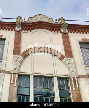 Eine Nahaufnahme eines architektonischen Details eines roten Ziegelbogens und geometrischer Stuckverzierungen an einer historischen Liberty-Stil-Fassade in Suzzara. Stockfoto