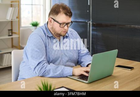 Konzentrierter Businessman-Freelancer, der an einem modernen Bürotisch an einem Laptop arbeitet, Remote-Arbeit Stockfoto