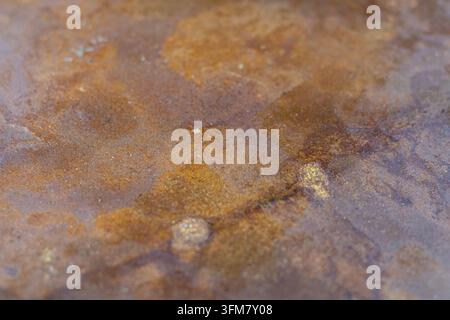 Nahaufnahme eines stark verwitterten Metallplattens, das mit geschichtetem Rost, Oxidation, Flecken und natürlichen Oberflächenunvollkommenheiten bedeckt ist und eine starke Stockfoto