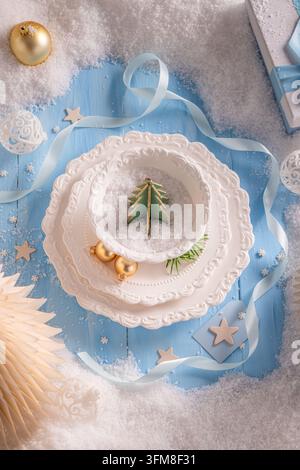 Blaues Tischthema mit verschneitem Weihnachtsdekor. Winziges Tannenbaumset auf Teller. Kreatives Feiertags-Esskonzept. Stockfoto