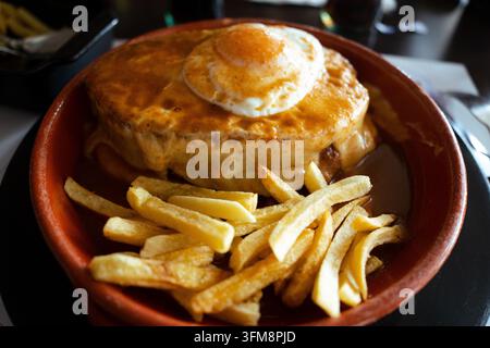 Francesinha, ein traditionelles portugiesisches Sandwich aus Porto, serviert mit geschmolzenem Käse und einer speziellen Soße Stockfoto