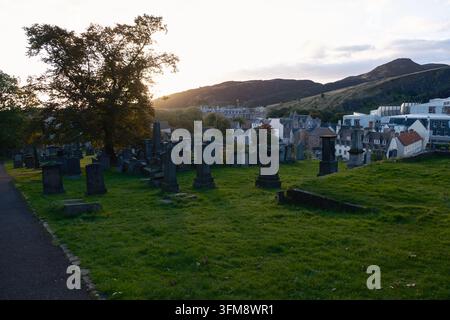 Blick bei Sonnenaufgang vom New Calton Burial Ground in Richtung Arthur's Seat und das schottische Parlament in Edinburgh, UK, am 26. September 2026. Stockfoto
