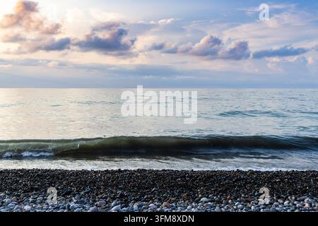 Blick auf die schwarze Meereswelle vom Kiesstrand in der Stadt Batumi, Georgien, bei einem Herbstsonnenuntergang Stockfoto