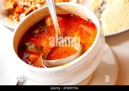 Marokkanisches königliches Couscous mit Fleischwürstchen und Gemüse, gekochtes Couscous und Gemüsebrühe serviert in einer Suppenschüssel mit Löffel Stockfoto