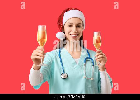 Weihnachliche Gesundheitsversorgungsparty, Krankenschwester mit Stethoskop und Weihnachtsmannmütze hält Champagnergläser für eine Feiertagsfeier in einem Krankenhaus oder einer medizinischen Klinik Stockfoto