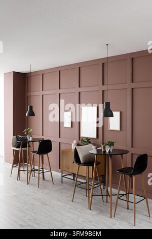 Modernes Café-Innenarchitekturdesign, Fernarbeit und Coworking-Bereich mit minimalistischen Möbeln und leeren Bilderrahmen an einer Terracotta-Wand Stockfoto