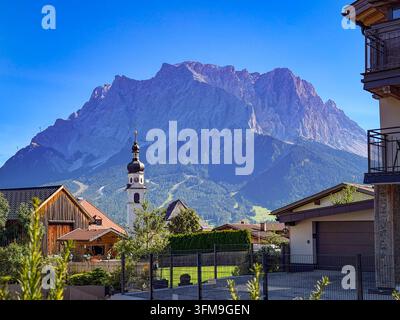 Lermoos, Tirol, Österreich: Ortsansicht mit der Pfarrkirche St. Katharina vor dem imposanten Wettersteinmassiv mit der Zugspitze. Traditionelle Tiroler Häuser und Kirchturm prägen das Ortsbild. Lermoos, Tirol, Österreich, Zugspitze, Wettersteingebirge, Pfarrkirche, St. Katharina, Kirche, Kirchturm, Alpen, Berglandschaft, Ortsansicht, Architektur, Tourismus, Tiroler Zugspitz Arena, Panorama. *** Lermoos, Tirol, Österreich: Blick auf die Stadt mit der Pfarrkirche St. Katharina vor dem imposanten Wettersteinmassiv, einschließlich der Zugspitze. Traditionelle Tiroler Häuser und der Kirchturm prägen das Stadtbild. Stockfoto
