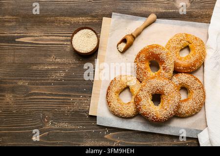 Gesundes Frühstücks- und Bäckereikonzept, frische Sesambagels auf einem Holzbrett mit Samen für die traditionelle handwerkliche Lebensmittelzubereitung und den kulinarischen Lebensstil Stockfoto