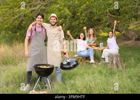 Sommer-Barbecue-Party, Freunde genießen ein Picknick im Freien und grillen Essen in der Natur mit einer vielfältigen Gruppe von Menschen, die zusammen am Wochenende im Park Spaß haben Stockfoto