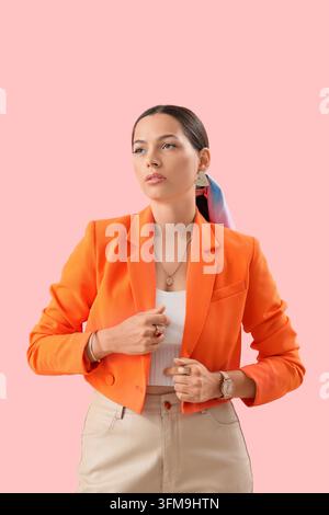 Persönliche Markenbildung und berufliches Selbstvertrauen, junge Frau in orangefarbenem Blazer posiert für ein Firmenporträt auf rosa Hintergrund Stockfoto