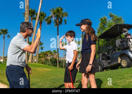 Golflehrer gibt Junior-Golfern während der Stunde ein High-Five Stockfoto
