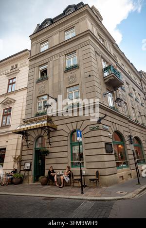 Historisches Eckgebäude mit einem Café und Außensitzgelegenheiten in der Altstadt von Krakau. Stockfoto