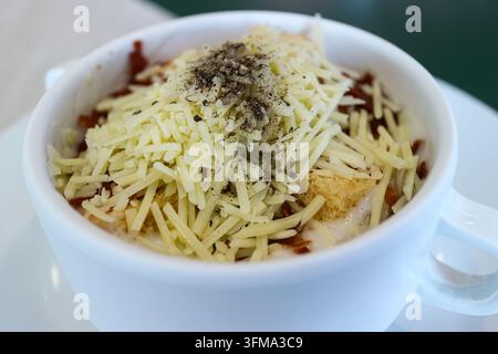 Nahaufnahme einer cremigen Thunfischsuppe, die mit Parmesan, Baconstückchen und Croutons in einer weißen Tasse in einem Café garniert ist Stockfoto