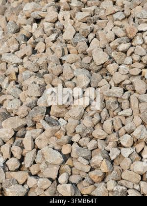 Kleine, unregelmäßige Kiessteine mit unterschiedlichen Texturen und neutralen Tönen, die einen natürlichen erdigen Hintergrund bilden Stockfoto