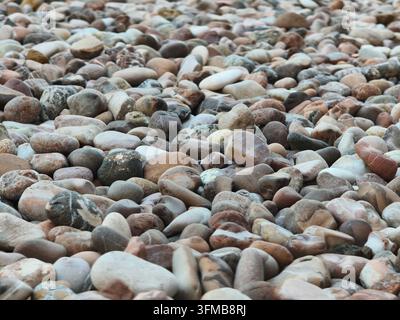 Nahaufnahme von verschiedenen Kieselsteinen und Steinen in verschiedenen Farben und Formen auf einer strukturierten Oberfläche Stockfoto