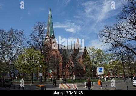 Rote Backsteinkirche der Trinitatiskirche mit hohem Turm, grünen Kupferdachdetails und gewölbten Fenstern, Berlin, Deutschland, April 2019 Stockfoto