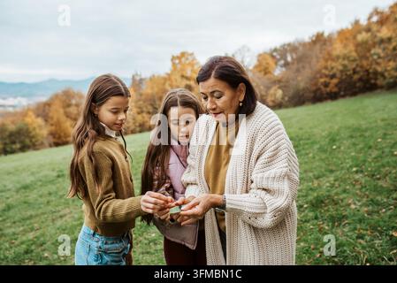 Großmutter verbringt Zeit mit den Enkelinnen, spaziert durch die herbstliche Natur. Stockfoto