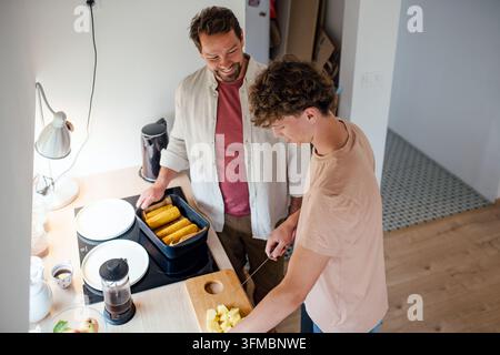 Teenager-Sohn hilft bei der Zubereitung des Frühstücks zu Hause. Stockfoto