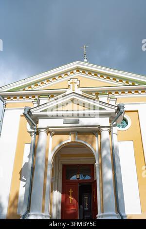 Ein ruhiger Kircheneingang mit Kreuzen und Säulen, aufgenommen in einer hellen Außenumgebung während des Tages. Die niedrige Kameraperspektive hebt den Eingang hervor Stockfoto