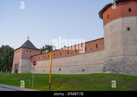 Eine ruhige Abendszene mit einer befestigten Mauer mit Türmen und umgebendem Gras, von der Seite aufgenommen. Die Struktur ist aus Ziegelsteinen und Stockfoto