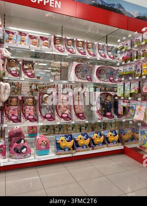 Pforzheim Deutschland 28. August 2026 Helle Spielzeuggeschäft-Gang mit Regalen voller verpackter Puppen, Plüschtiere und Enten-Rutschfahrzeuge sowie Babyzubehör und Stockfoto