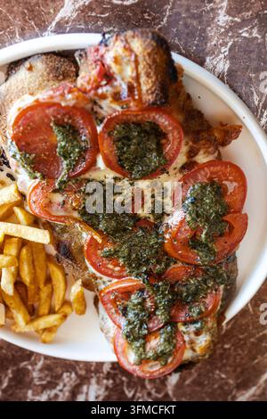Milanesa napolitana mit Pesto, Tomate, Mozzarella und Pommes frites Stockfoto