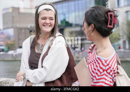 Junge Studentinnen, die sich draußen unterhalten, reden und lächeln Stockfoto
