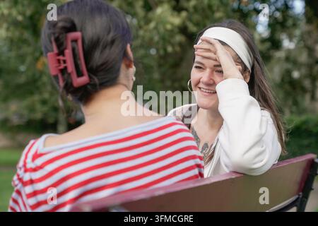 Glückliche junge Frauenfreundinnen unterhalten sich im Park Stockfoto