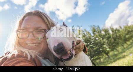 Zweijähriger Junge geht mit einem Hund in einem Apfelgarten Stockfoto