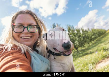 Zweijähriger Junge geht mit einem Hund in einem Apfelgarten Stockfoto