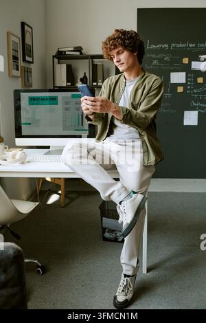 Mann verwendet Smartphone am Schreibtisch in kreativem modernem Büro Stockfoto