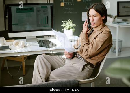Erwachsener Geschäftsmann telefoniert am Bürotisch Stockfoto