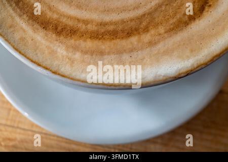 Nahaufnahme des Schaumstoffs auf einem flachen weißen Kaffee in Großbritannien. Stockfoto