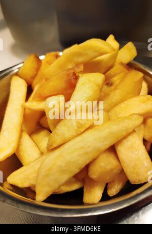 Ein appetitlicher Schnappschuss eines Haufens goldener Pommes frites, serviert in einer silbernen Metallschale. Tiefgebraten mit einer knusprigen, strukturierten Außenseite und einem weichen Inneren. Dieser c Stockfoto