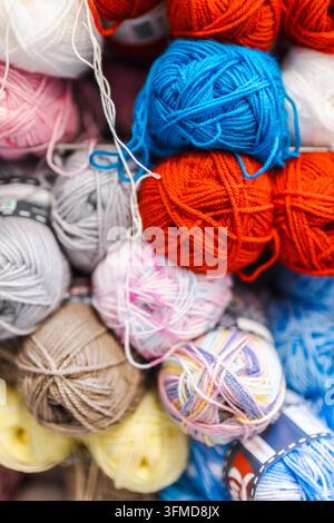 Bunte Wollknäuel füllen eine Handarbeitsladen-Auslage in Orange, Blau, Rosa, Grau, Beige und Gelb. Stockfoto