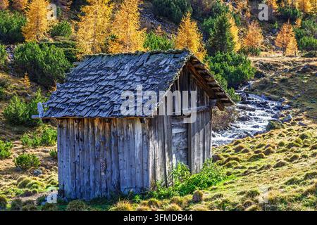 Rustikales Holzschuppen neben einem Bach im Herbst Stockfoto