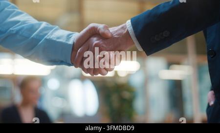 Zuschnitt auf zwei unerkennbare kaukasische Geschäftsleute, die sich im Büro die Hand geben. Geschäftsleute, Händeschütteln, Nahaufnahme, unbekannte Männer, Agenten, Begrüßung in Stockfoto