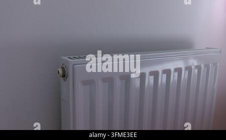Ein moderner weißer Plattenheizkörper ist ordentlich an einer hellen Wand montiert und bietet ein sauberes und funktionales Heizelement Stockfoto