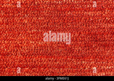 Makroaufnahme von weichem orangefarbenem Fleece-Stoff, der feine Wollfasern und die gestrickte Struktur zeigt. Warme Studiolichtbeleuchtung hebt die plüschige Oberflächentextur hervor Stockfoto