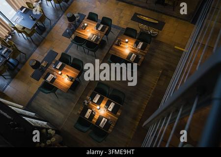 Stilvoller Essbereich eines gemütlichen modernen Restaurants, rustikales und zeitgenössisches Design mit Holztischen und warmer Beleuchtung, Ansicht von oben. Stockfoto