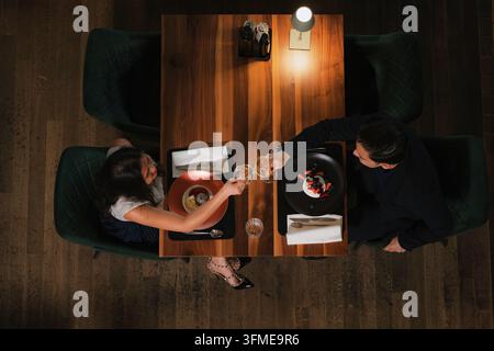 Romantisches elegantes Paar bei einem Abendessen, das das Servieren und schmackhafte Essen in einem modernen Restaurantinterieur genießt, Blick von oben. Stockfoto