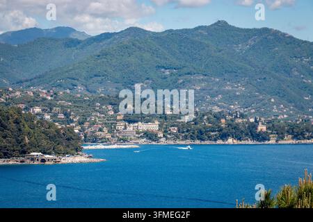 Weite Küstenansicht von Portofino über das blaue Meer in Richtung Santa Margherita Ligure, mit Küstenlinie, Bergen, Kiefern, kleinen Booten, Wolken und c Stockfoto