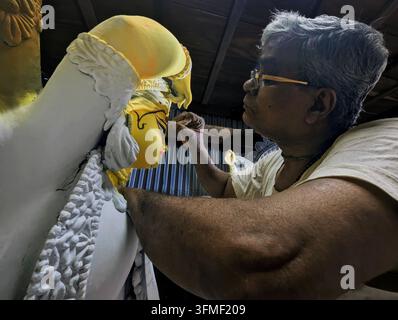 CHITTAGONG, BANGLADESCH - 28. SEPTEMBER 2026: Da das hinduistische Fest Durga Puja bald bevorsteht, werden die Werkstätten für die Herstellung von Götzenstatuen jeden Tag geschäftiger. Von morgens bis spät abends arbeiten die Handwerker mit Ton, Farben und Pinseln, um die Götzenstatuen rechtzeitig fertigzustellen. Einige sind damit beschäftigt, die Statuen zu formen, während andere an den feineren Details arbeiten, malen und dekorieren. Jede Statue erfordert Tage voller Geduld und harter Arbeit, bevor sie schließlich ihre vollständige Form annimmt. Die schwach beleuchteten Werkstätten, der Geruch von Ton und die geschäftigen Hände der Handwerker schaffen zusammen eine andere Art von Atmosphäre – eine th Stockfoto